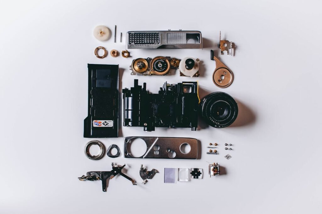 Flat lay of various disassembled camera parts on a white surface showcasing intricate details.